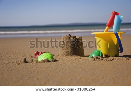childs sand bucket and toys on scenic sunny beach with waves