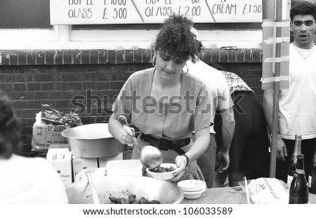 LONDON - JULY 21: A woman ladles strawberries at the Italian street party in Warner Street, Clerkenwell on July 21, 1990 in London. The event follows the annual procession of St.Mary of Carmel.