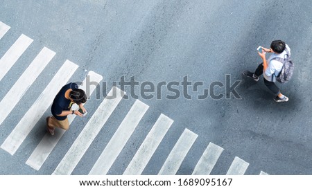 Human life in Social distance. Aerial top view with blur man with smartphone walking converse of other people at pedestrian crosswalk on grey pavement street road with empty space.