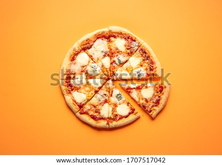 Sliced cheese pizza on an orange background above view. Pizza sliced in eight. Delicious homemade pizza top view. Pizza made only with cheese and tomato sauce.