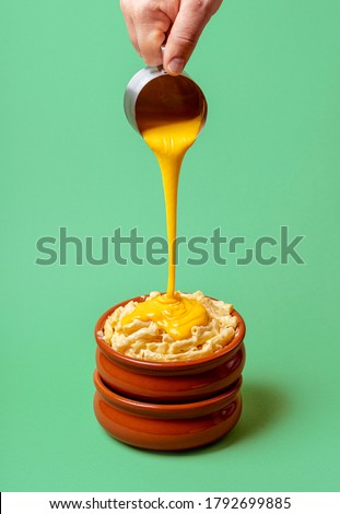 Cooking mac and cheese with melted cheddar cheese dripping over boiled macaroni, isolated on a green background. Pouring cheese on pasta. Hot food.