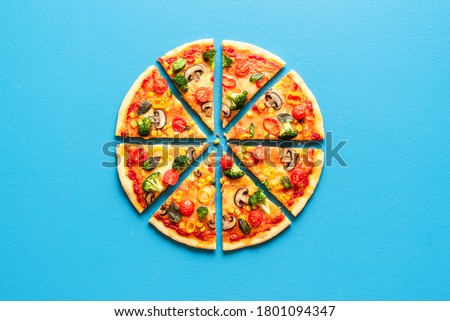 Top view with a sliced pizza primavera on a blue table. Vegetarian pizza flat lay. Sliced pizza isolated on a blue colored background.