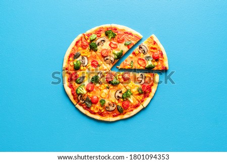 Vegetarian pizza isolated on a blue colored background. Sliced pizza top view on blue table. Pizza with cheese, tomato sauce and vegetables.