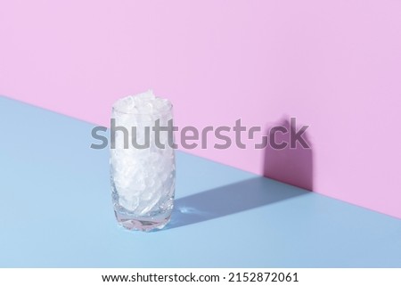 Close-up with a glass full of crushed ice, isolated on a blue background. Glass with ice in bright light against colorful background. Stockfoto © 