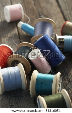 blue, turquoise, orange, pink and green cotton reels on a rough wooden table