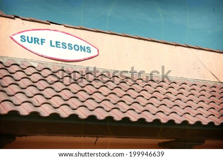 aged and worn vintage photo of surf lessons sign on building
