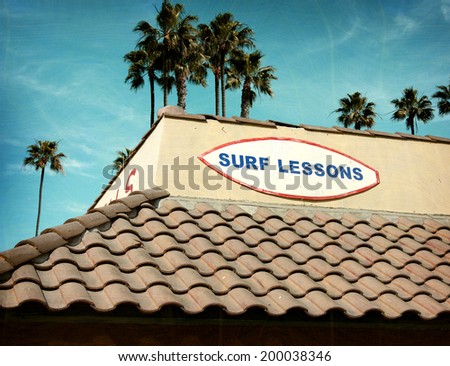 aged and worn vintage photo of surf lessons sign with palm trees