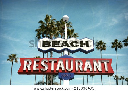 aged and worn vintage photo of neon sign on beach with palm trees
