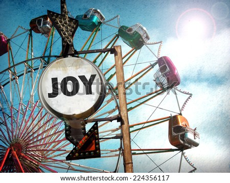 aged and worn vintage photo of ferris wheel and joy sign with bright sun flare