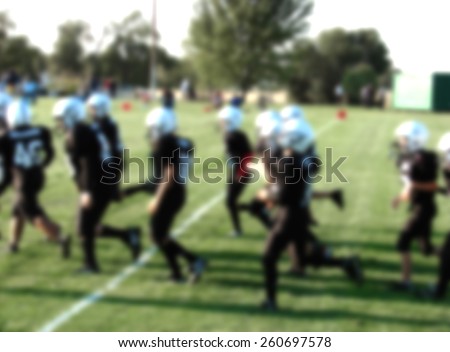 blurred background with youth american football players in action