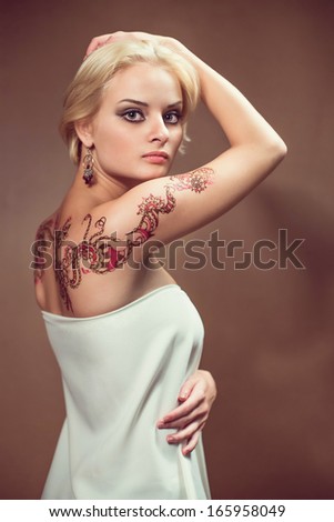 Beautiful blond woman with henna tattoo on her back.