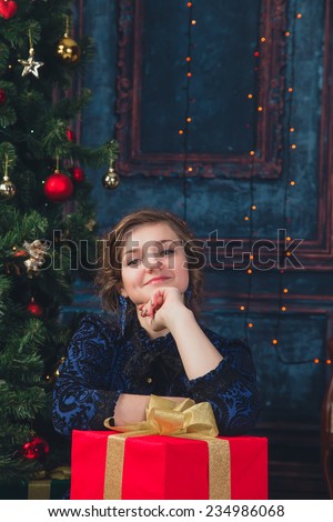 Young girl with  gift on the Christmas tree background