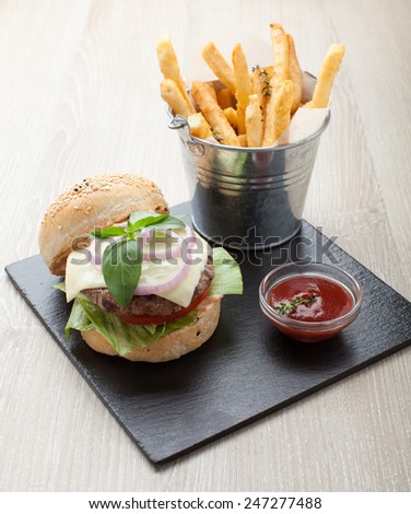 Healthy wheat sandwich burger with beef steak, cheese, tomato, lettuce, onion, basil, fried potato and ketchup  served for eating