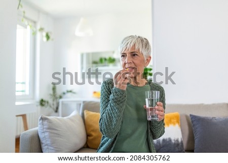 Senior woman takes pill with glass of water in hand. Stressed female drinking sedated antidepressant meds. Woman feels depressed, taking drugs. Medicines at work Stock foto © 