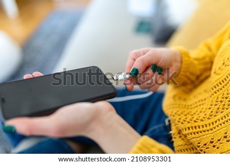 Woman hands plugging a charger in a smart phone. Woman using smartphone with powerbank, charging power to smart phone. Woman charging battery on mobile phone at home Photo stock © 