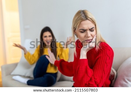 Two female friends sitting on sofa and arguing with each other. Friendship, quarrel, female disagreement, copy space. Angry friends or roommates sitting on a sofa in the living room at home Foto stock © 