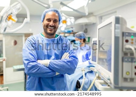 Anesthetist Working In Operating Theatre Wearing Protecive Gear checking monitors while sedating patient before surgical procedure in hospital Сток-фото © 