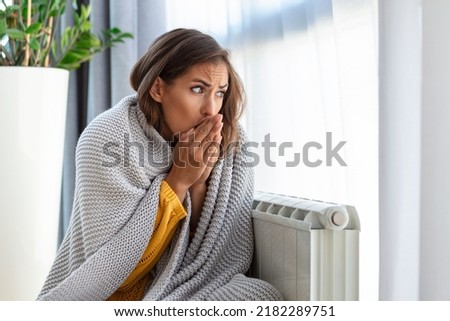 Woman freezing at home, sitting by the cold radiator. Woman with home heating problem feeling cold Stock foto © 