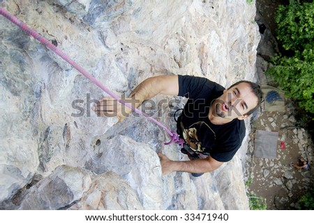 Climber overpassing a difficult part in the wall while rock climbing in Phi Phi Islands, Thailand