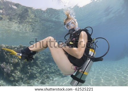 Adult Female scuba diver in bikini diving in shallow tropical water