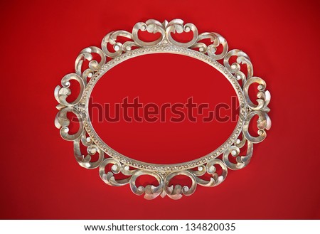 Vintage silver oval frame on red wall