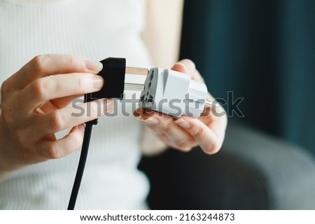 Woman applies universal travel adapter electrical plug converter power socket ストックフォト © 