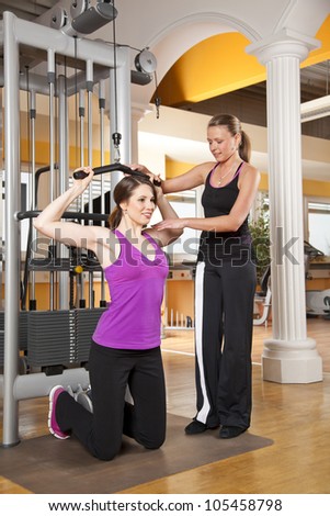 smiling young woman with her female coach training latissimus
