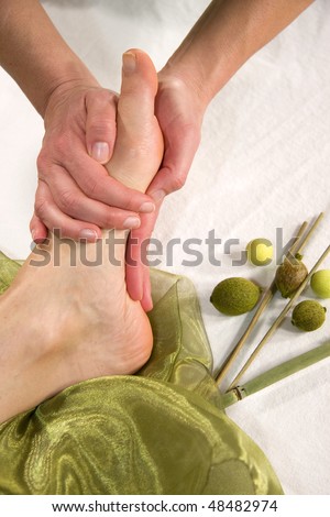 a wellness composition with a closeup of a foot of a mature natural woman having a foot massage