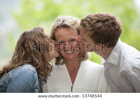 mother being kissed by daughter and son
