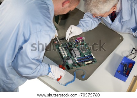 IT engineers doing repairs on a motherboard