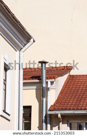 Old house tiled roof with gutter and ventilation pipe