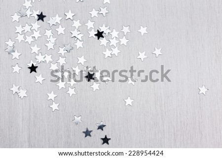 Silver star confetti on brushed metal texture