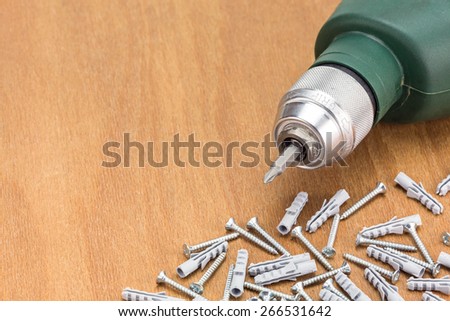 Electric drill and screws on wooden background
