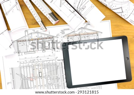 tablet computer, architectural blueprint and rolls of plans