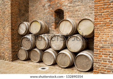 Many vintage wooden barrels against a brick wall