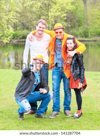 AMSTERDAM -APRIL 30 : Dutch youth wear orange clothes, hats in honor of the House of Orange-Nassau, pose for group portrait on Queen\'s Day, national holiday, April 30, 2013, Amsterdam, The Netherlands