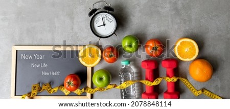 2021 and 2022 on alarm clock with workout planing for dieting. New Year New Life and New Health,  Sport exercise equipment workout andÂ gym nutrition fresh fruits for fitness
