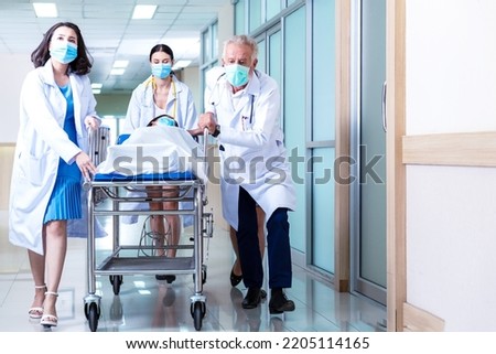 Team medical doctor pushing stretcher gurney bed corridor with female patient in hospital. Health care Concept ストックフォト © 
