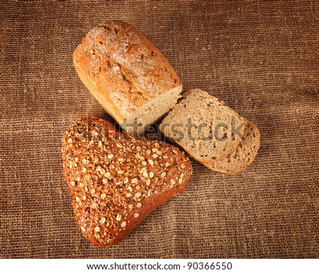 Sliced bread and bread with grains, burlap vintage background