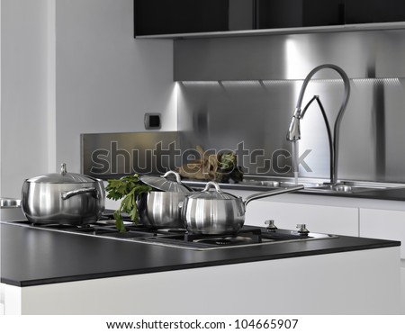 detail of steel saucepans with parsley in a modern kitchen