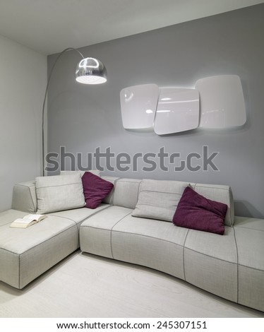 detail of fabric sofa with purple pillow in the modern living room with heater on the wall and  floor lamp