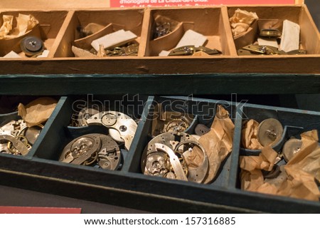 Old watch and clock pieces in wooden boxes.