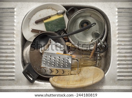 Dirty dishes, utensils in the metal sink background