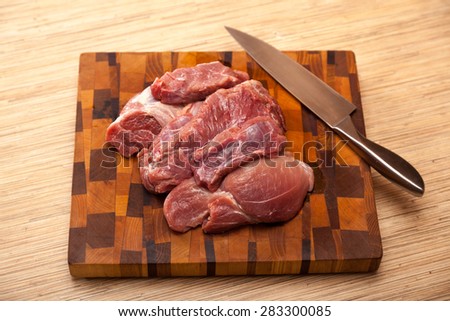 the cut meat and steel knife on a wooden chopping board