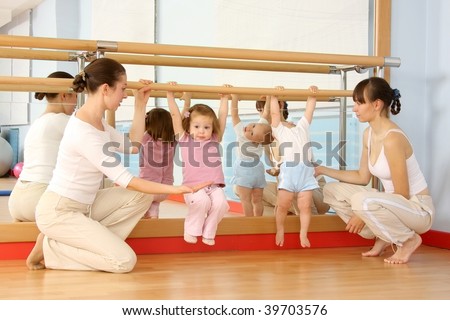 Mother and the child are engaged with the instructor in a sports hall