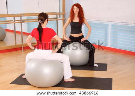 The pregnant woman with the instructor is engaged in gymnastics in a sports hall