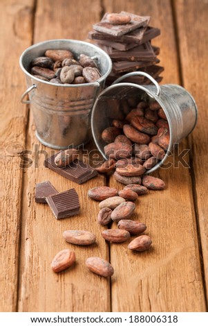 Cocoa beans in two tin buckets and broken dark chocolate