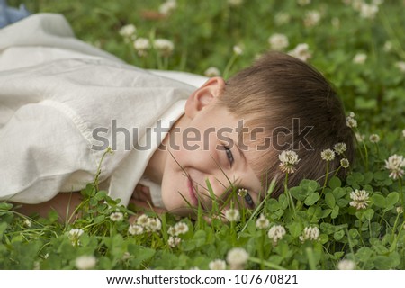 Young Caucasian Boy lying in the grass on his stomach and a cute look on his face. Four to  Five years old