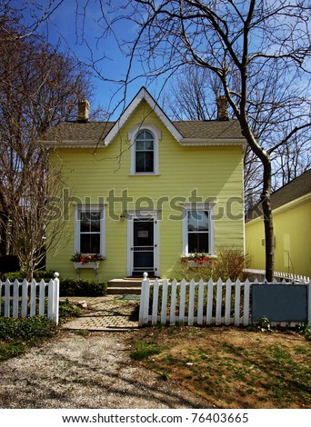 a yellow house with white picket fence