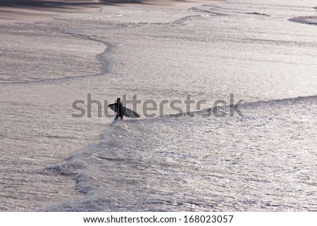 PUTSBOROUGH SANDS, ENGLAND - DEC 11: Lone surfer making their way up the beach late in the day on December 11, 2013. This stretch of coastline has long been popular with experienced surfers in the UK